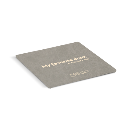 Grey coaster with text 'My favorite drink is the next one' on a white background