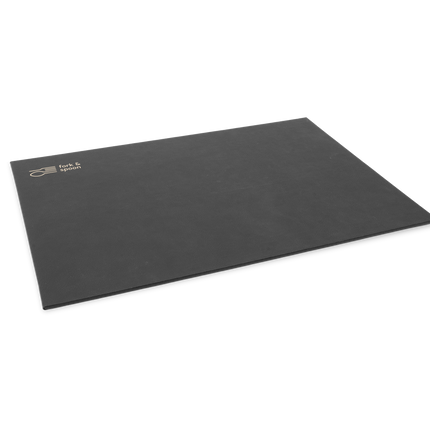 A black rectangular placemat made from vegan leather, with a subtle textured surface and visible stitching along the edges.