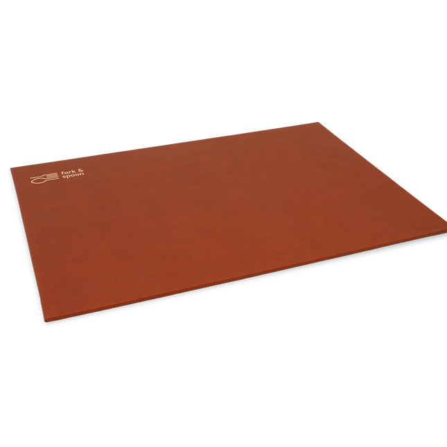 A brown rectangular placemat made from vegan leather, with a subtle textured surface and visible stitching along the edges.